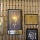 A wall covered in rows of beer cans, with additional art such as a framed portrait of JFK on the wall